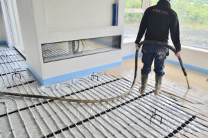 ADM Floor Screed Worker Pouring Liquid Screed Over Pipes 4